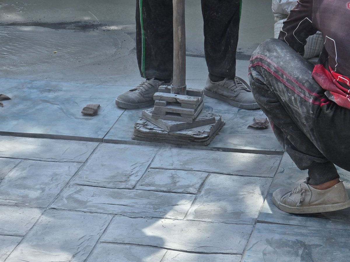 Skilled craftsmen finishing a stamped concrete surface on a Phoenix hardscaping project